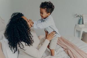 gravid afroamerikansk dam som leker med sin son hemma foto