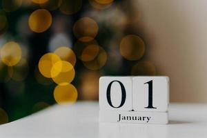vintertid, första januari. kalender med siffror och månad på vitt skrivbord mot shing lights och nyårsbakgrund. första månaden på året foto