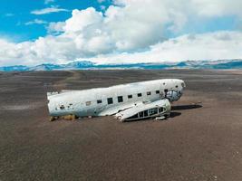 Flygfoto av det gamla kraschade planet övergivet på solheimasandur strand nära vik, island. foto