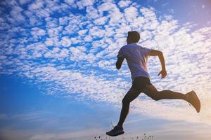 siluett av ung man kör sprint på väg. fit löpare fitness löpare under utomhusträning med solnedgång bakgrund. foto