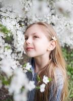 söt liten flicka i en blommande vårträdgård foto