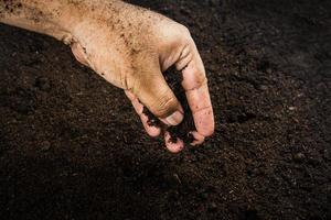 händerna smutsiga med lera, jord bakgrund foto