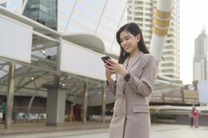 en ung vacker affärskvinna använder smart telefon i modern stad, affärsteknik, stadslivsstilskoncept foto