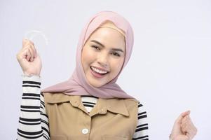 en ung muslimsk kvinna som håller invisalign hängslen i studio, tandvård och ortodontisk koncept.. foto