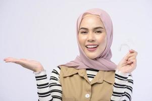 en ung muslimsk kvinna som håller invisalign hängslen i studio, tandvård och ortodontisk koncept.. foto
