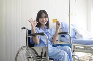 en ung patient kvinna håller kreditkort, erkännande på sjukhus, hälso-och sjukvård koncept foto