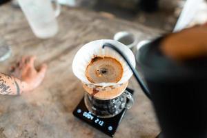 droppa kaffe, hälla hett vatten i vattenkokaren i kaffet, brygga kaffe foto