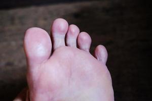 stängda kvinnliga fötter med franska naglar på trägolv, hälsovård och medicinsk koncept foto