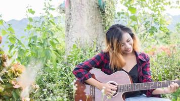 ung kvinnas hand spelar gitarr. utomhus foto