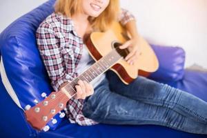 ung hipsterkvinna som spelar en gitarr. foto