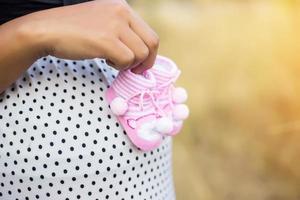 gravid kvinna som håller babyskor foto