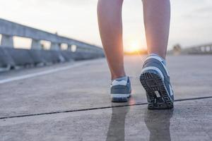 vägen till framgång, springa på väg med sportskor, hälsosam livsstil sport kvinna löpning, kvinnliga ben med sneakers joggar på kvällen förbereda sig för maraton foto