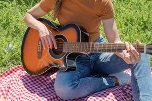 closeuo av ung kvinna som spelar gitarr på en picknick foto