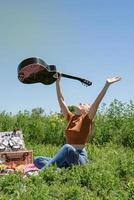 ung kvinna spelar gitarr på en picknick foto