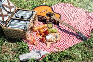 närbild av picknickkorg med drinkar och mat på gräset foto