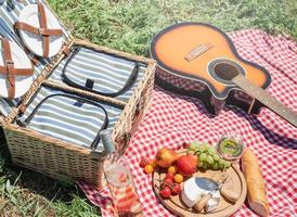 närbild av picknickkorg med drinkar och mat på gräset foto