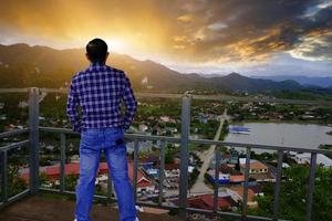 porträtt stilig man turist stående på en populär utsiktspunkt ovanför vieng xay-grottornas landskap i pha nang mone-grottan, vieng xay-distriktet, houaphanh-provinsen, laos. foto