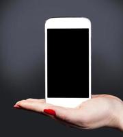 vit smartphone på en kvinnlig hand foto