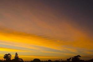 himlen är en horisontell linje av gul-orange och färgglada färger i den vackra kvällen mitt i naturen som är fridfull, varm och romantisk på landsbygden och är extremt vacker. foto