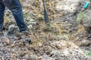 trädgårdsmästare gräver jorden med sin utrustning för trädgårdsarbete och förbereder mark för plantering. foto