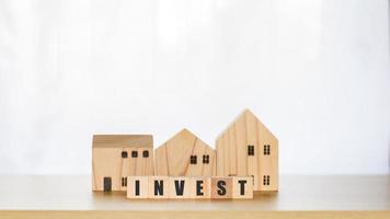 fastighetsinvestering koncept. träblock med textinvestering och modellhus, fastighetstillväxt i framtiden, finans, bank, utlåning och handel. foto