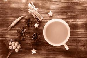 kaffe, kryddor och kottar på en trä bakgrund. jul koncept. en kopp varmt kaffe med mjölk, kanel och chili på ett träbord. foto