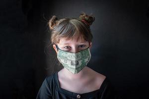 den verkliga kostnaden för en pandemi med medicinsk mask gjord av pengar i ansiktet på barnet foto