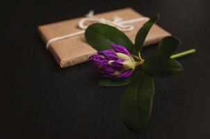 lila azaleablomma med present i hantverksförpackning foto