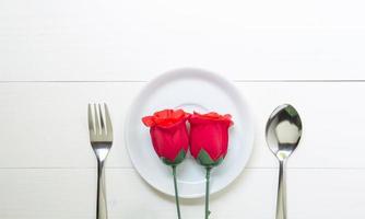 presentgåva med röd ros blomma och fat och sked och gaffel på träbord, 14 februari av kärleksdagen med romantisk kopia utrymme, alla hjärtans semester koncept, ovanifrån. foto