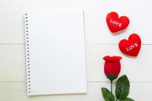 närvarande röd ros blomma och anteckningsbok och hjärta form med kopia utrymme på träbord, 14 februari av kärleksdagen med romantiska, alla hjärtans semester koncept. foto