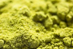 grönt pulver japanskt matcha te närbild. pulvret innehåller en blandning av vita granulat av kokosmjölk. matcha latte i torr form. bakgrund, textur foto