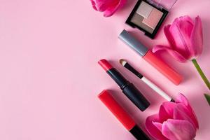 uppsättning kosmetika och blommor på en rosa bakgrund. smink- och skönhetsprodukter. foto