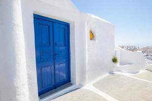 gammal blå dörr och rosa blommor, traditionell grekisk arkitektur, ön Santorini, Grekland. vackra detaljer på ön santorini, vita hus, blå dörrar och fönsterluckor, Egeiska havet. foto