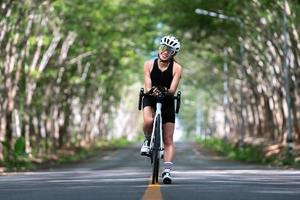 glad kvinna som cyklar idrottare förbereder sig för att cykla på gata, väg, med hög hastighet för träningshobby och tävling i professionell turné foto