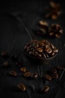kaffebönor i en vintage sked på svart bakgrund, vinkelvy foto