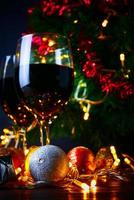 rött vin i glas klart, julgran och prydnad på träbord redo för att fira. foto