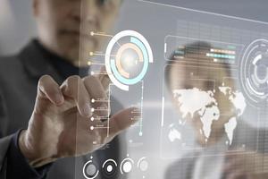 två asiatiska affärsmän interagerar med futuristisk virtuell pekskärm medan de analyserar affärsinformationsdata foto