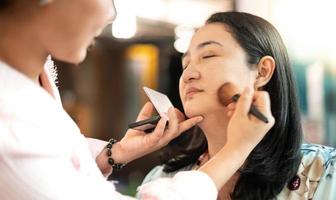 unga vackra asiatiska förbereda applicera make-up av professionell make-up artist. foto