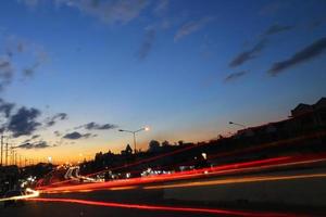 utsikt över vägen i kullen genom liten stad vid solnedgången och har många bilar ljus. foto