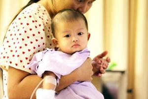 asiatisk baby på sjukhus med mamma. sjukt barn med mamma på sjukhus foto