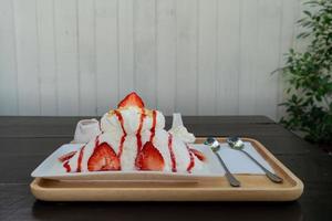 jordgubb kakigori japansk rakad is efterrätt mjölksmak eller binsu korea dessert servera på vit tallrik med jordgubbssås och pålägg på bordet foto