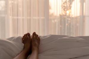 kvinna fötter slappna av på vit blacket på morgonen foto