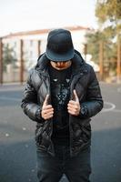 ung trendig kille klädd i svart keps och en svart jacka på gatan foto