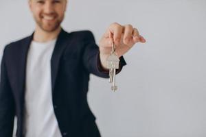 porträtt av glada professionella fastighetsmäklare som håller urklipp och visar nycklar i handen, selektivt fokus. foto
