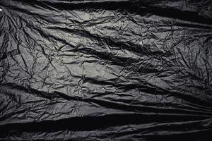en genomskinlig stretchplastfolie på svart bakgrund. realistisk plastfoliestruktur för överlagring och effekt. skrynkligt plastmönster för kreativ och dekorativ design. foto