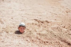 ung pojke huvudet på sand bära panama hatt. rolig sommarlov. foto