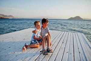 två bröder sitter på turkiet resort på piren mot Medelhavet. foto