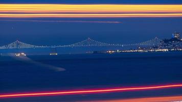 Bay bridge i fjärran med lång exponering trafikljus i förgrunden foto