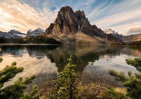 stenigt berg med tall reflektion på cerulean sjön i assiniboine provinsparken foto