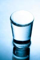 glas fyllt till brädden med vatten i blått monokromt. foto